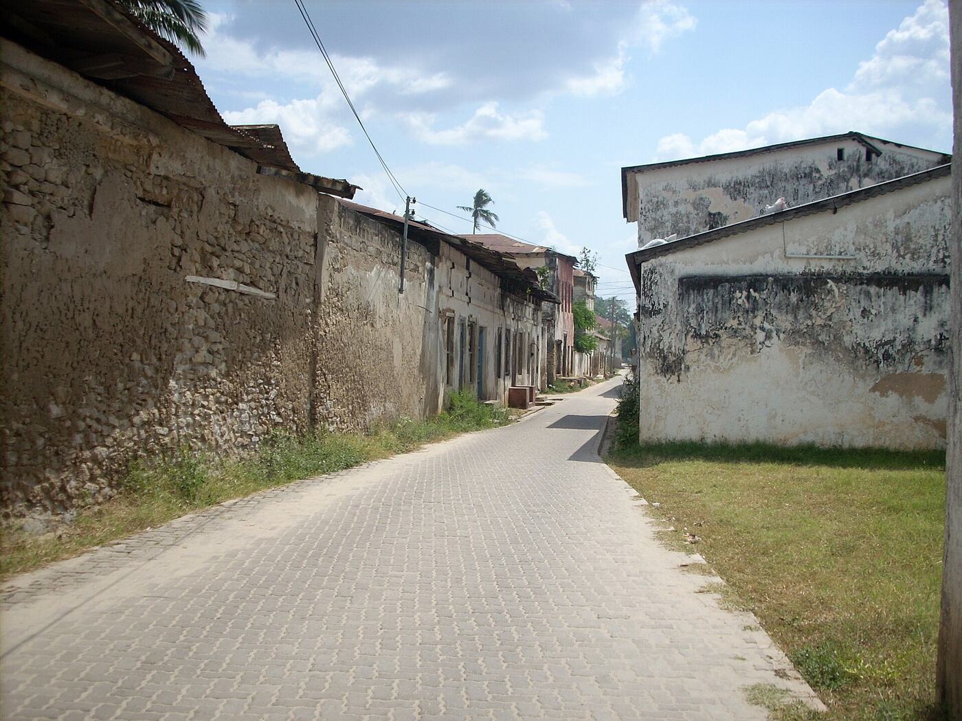 A paved street in Bagamoyo's old town between weathered stone walls